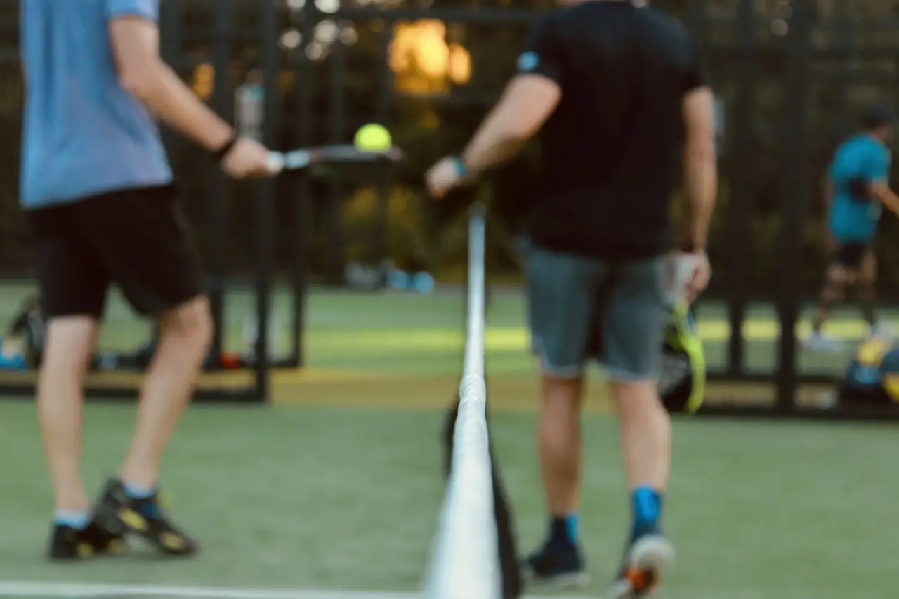 Two players at the net in the last of the evening light.