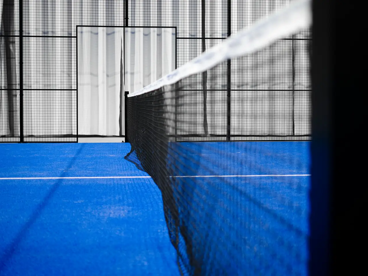 The net and the mesh wall of a padel court, seen close up.